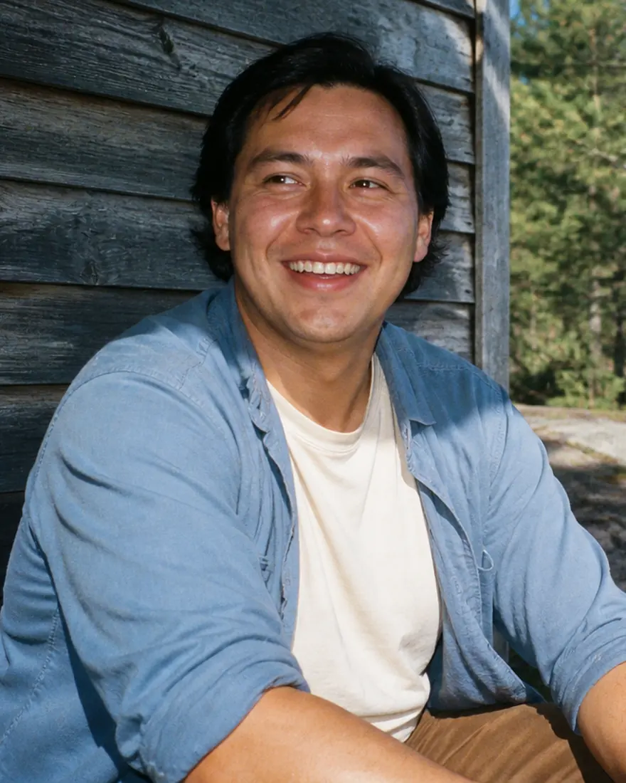 A man smiling beside a lakeside cabin